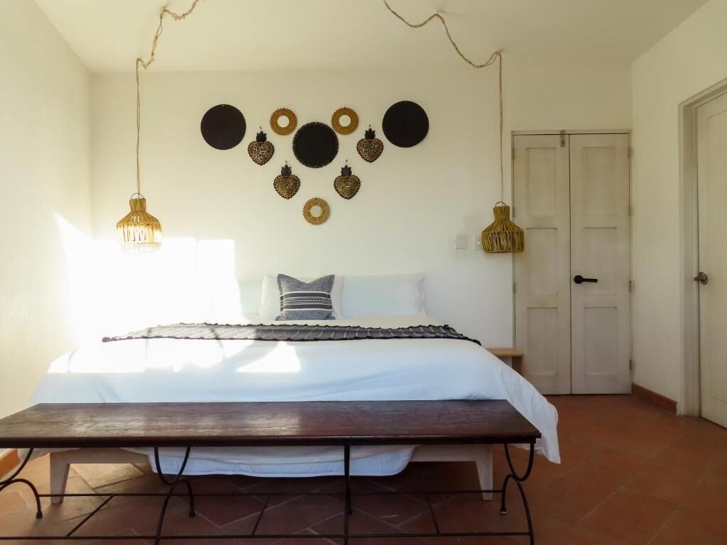 Un dormitorio con cama, lámparas de noche, un reloj de pared y una puerta.