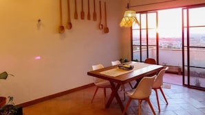 A dining area with a wooden table, white chairs, and a view through large windows. - Casa Espiral (San Miguel de Allende)