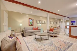 A living room with a sofa, armchairs, a coffee table, and a rug. There are framed pictures on the wall and a television on the right. - Walk to Charleston’s Best Dining and Entertainment (Charleston)
