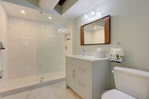 Ein modernes Badezimmer mit einer gläsernen Duschkabine, einem weißen Waschbecken und einer Toilette.