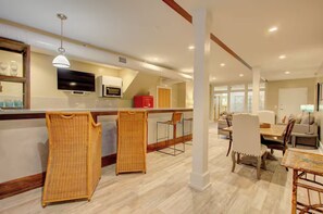 A modern kitchen with a microwave, a red refrigerator, and a dining area with wicker chairs and a table. - Walk to Charleston’s Best Dining and Entertainment (Charleston)