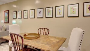 A dining area with a wooden table and chairs, framed artwork on the wall, and a sofa in the background. - Walk to Charleston’s Best Dining and Entertainment (Charleston)