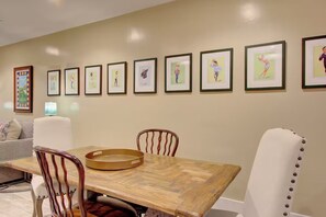 A dining area with a wooden table and chairs, framed artwork on the wall, and a sofa in the background. - Walk to Charleston’s Best Dining and Entertainment (Charleston)