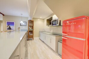 A modern kitchen with a red refrigerator, white cabinetry, and a wooden bar area. - Walk to Charleston’s Best Dining and Entertainment (Charleston)