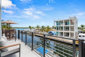 A balcony with a view of a marina, a pool, and a multi-story building under construction.