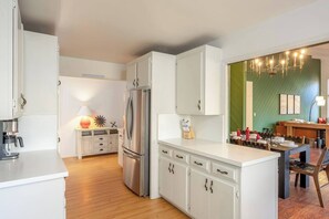 Eine moderne Küche mit weißen Schränken, einem Edelstahlkühlschrank und einem Essbereich mit Holztisch und Stühlen.