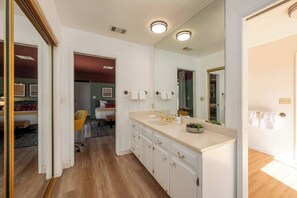 A bathroom with a large mirror, a sink, and a toilet. There is a door leading to another room. - Sierra Haus | 4mi to Sequoia + Hot Tub + Game Room (Three Rivers)