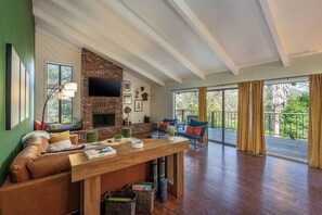 A spacious living room with a fireplace, a large window, and a balcony. - Sierra Haus | 4mi to Sequoia + Hot Tub + Game Room (Three Rivers)