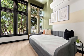 A modern bedroom with a large bed, multiple windows, and artwork on the wall. - Explore Downtown Fun | Walk to Petco Park & More!! (San Diego)