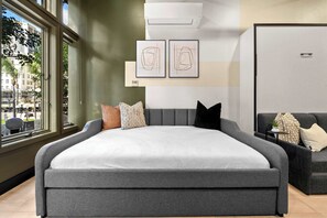A modern bedroom with a large bed, a grey sofa, and artwork on the wall. - Stay Central Near Petco Park & Gaslamp (San Diego)