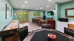 Quarto com mesa de boliche, sofá, televisão e micro-ondas.