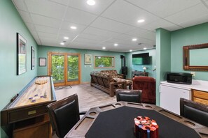 A room with a shuffleboard table, a sofa, a television, and a microwave. - Giants Ridge lakefront Villa 4bdrm with gameroom (Biwabik)