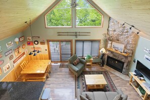 A spacious loft with a high ceiling, a stone fireplace, a television, and a dining area. - Giants Ridge lakefront Villa 4bdrm with gameroom (Biwabik)