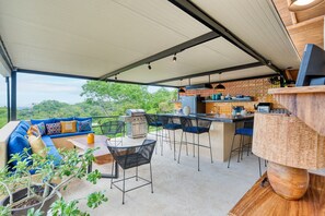 Eine Außenpatio mit Barbereich, Sitzgelegenheiten und Grill.