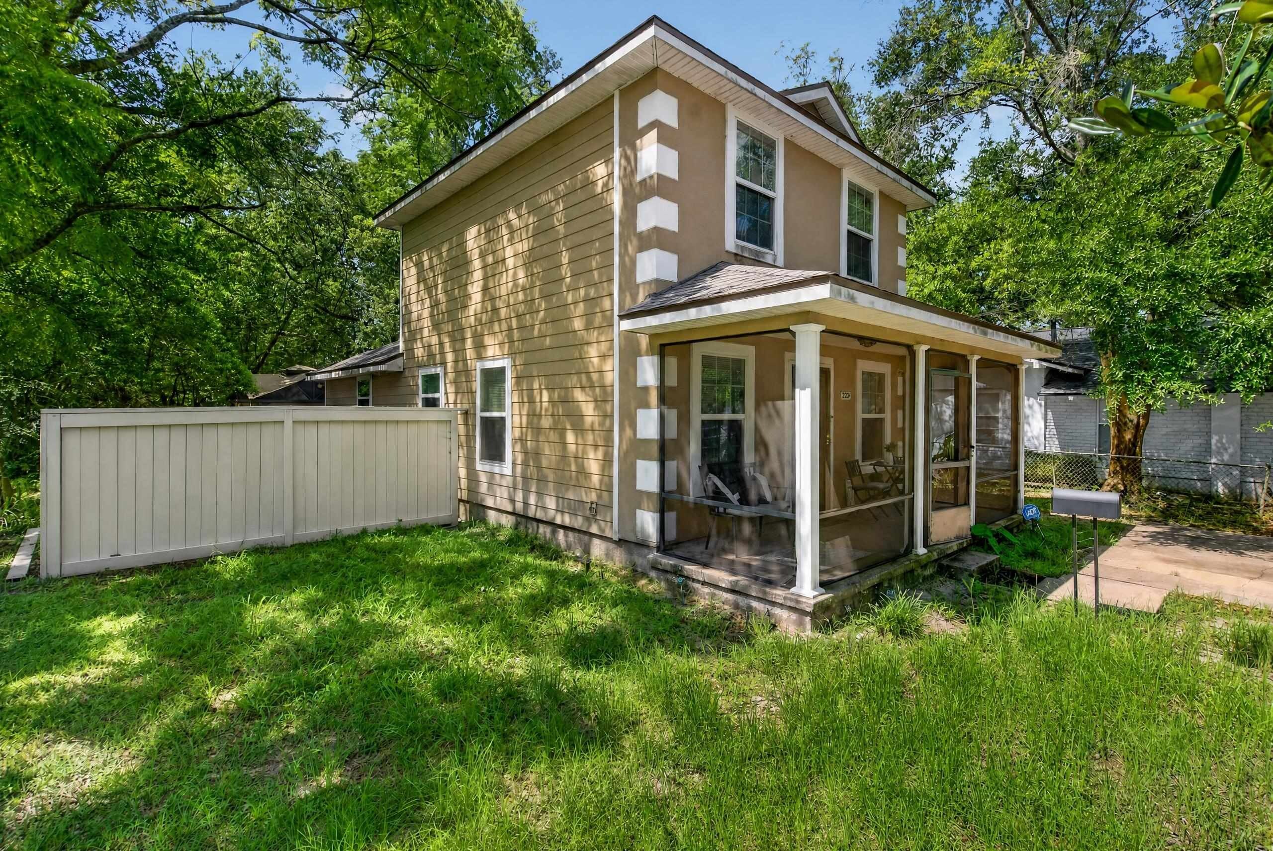 A two-story house with a covered porch and a fenced backyard.