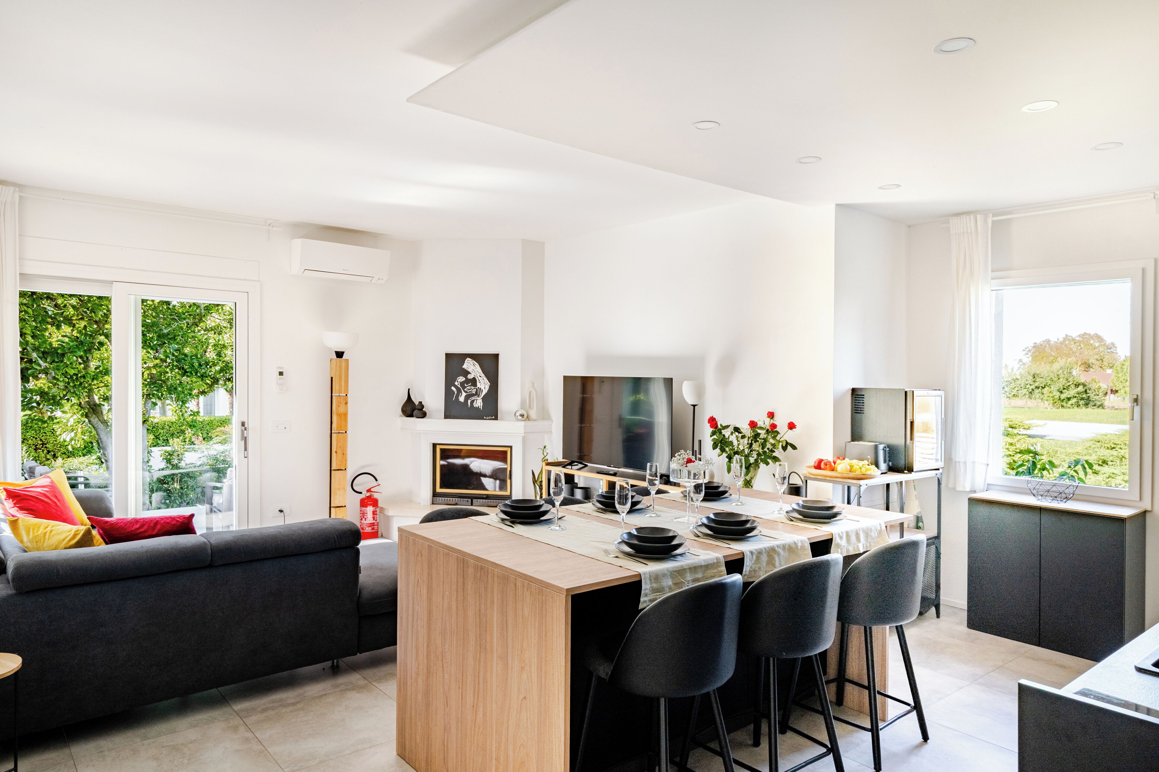 Una cucina moderna con isola centrale, zona pranzo con sedie, un divano e una televisione.