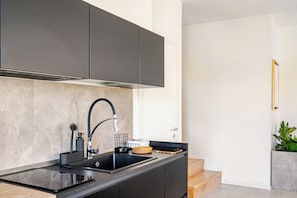 A modern kitchen with a black countertop, stainless steel sink, and grey cabinets. - Villa with garden and free parking—25min from Venice—3 bedrooms,2 bathrooms, A/C (Veneto)