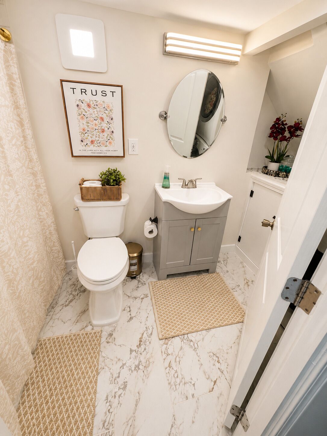 Un bagno con toilette, lavandino, specchio e una citazione incorniciata appesa al muro.