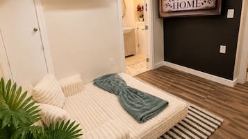 A bedroom with a bed, a potted plant, and a wall-mounted air conditioner.