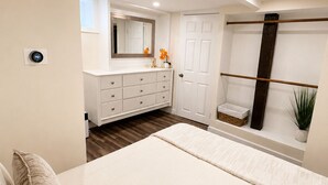 A bedroom with a bed, dresser, mirror, and a window with a plant.
