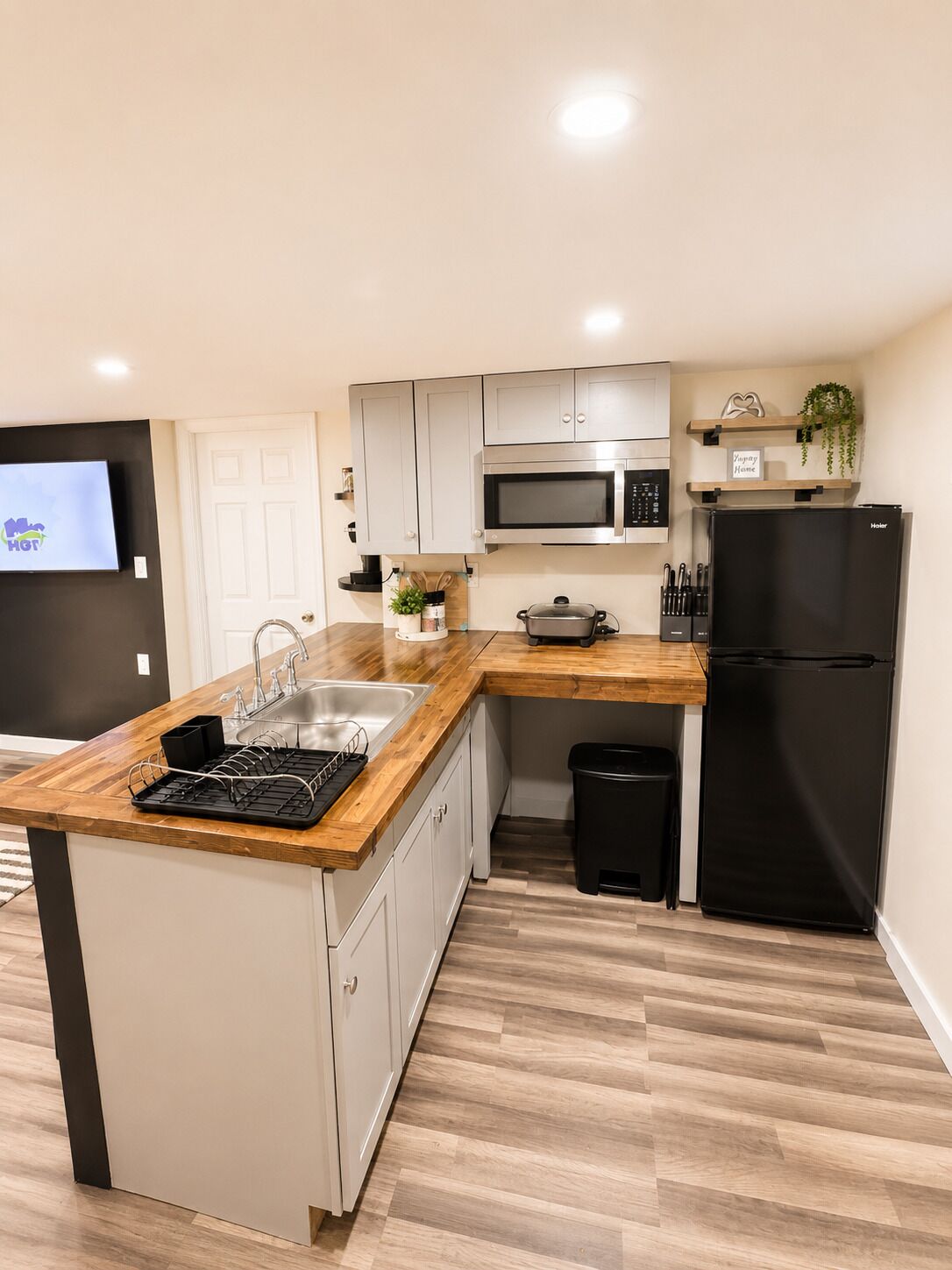 Una cocina moderna con encimera de madera, electrodomésticos de acero inoxidable y un cubo de basura negro.