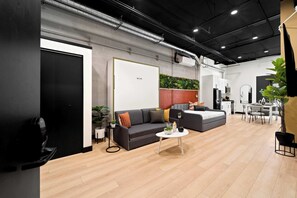 A modern interior with a sofa, coffee table, and a dining area with chairs and a table. - Explore Petco Park & Gaslamp Nightlife - Sleeps 4! (San Diego)