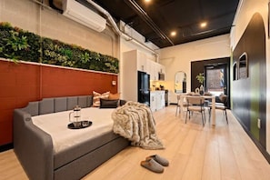 Ein modernes Wohnzimmer mit einer Couch, einem Essbereich und einer Küche im Hintergrund.