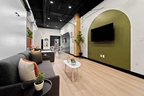 A modern living room with a grey sofa, a coffee table, and a TV mounted on a green wall. - Explore Petco Park & Gaslamp Nightlife - Sleeps 4! (San Diego)