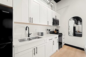 A modern kitchen with white cabinetry, stainless steel appliances, and a black stove. - Explore Petco Park & Gaslamp Nightlife - Sleeps 4! (San Diego)