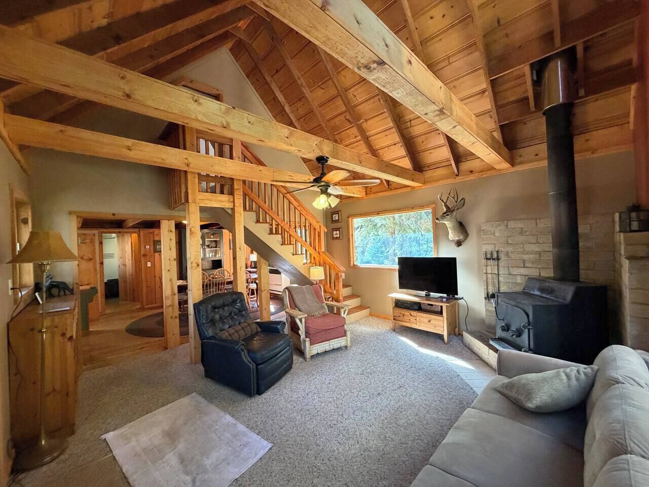 A spacious living area with a fireplace, a television, and a staircase leading to another room.