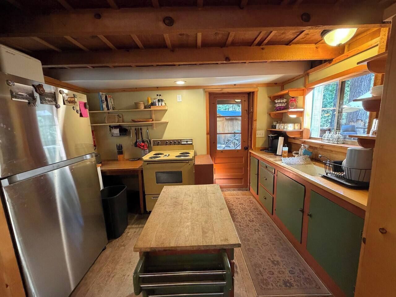 Una cocina compacta con refrigerador, estufa y armarios de madera.