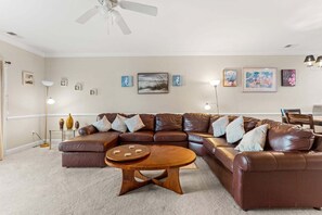 Ein modernes Wohnzimmer mit einer Eckcouch, einem Couchtisch und Kunstwerken an den Wänden.