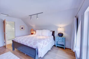 A bedroom with a bed, bedside table, lamp, and a door. - Historic Charleston Charm, Unbeatable Location (Charleston)