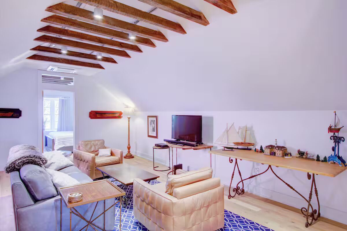 Un salon moderne avec un plafond haut, un téléviseur à écran plat, une table en bois et un canapé.