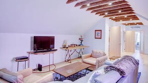 Uma sala de estar moderna com televisão de tela plana, mesa de centro de madeira e um sofá.