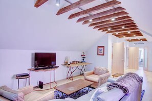 Ein modernes Wohnzimmer mit Flachbildfernseher, Couchtisch aus Holz und einer Couch.