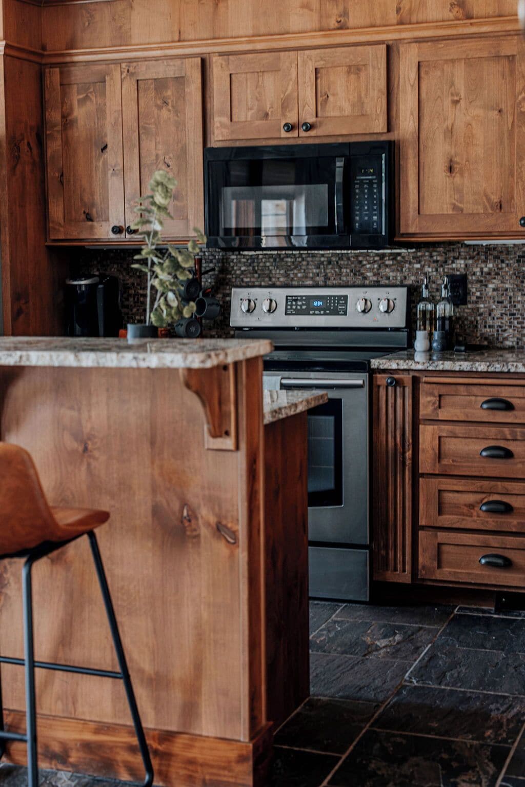 A kitchen with wooden cabinets, a stainless steel stove, and a granite countertop.