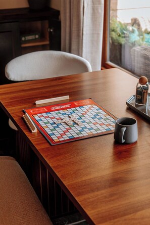 A Scrabble game on a wooden table with a coffee mug beside it.