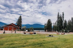 A rural property with a red barn, open fields, and a mountainous backdrop.