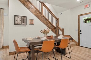Ein Essbereich mit einer Holztreppe, einer weißen Tür mit Ausgangsschild und einem gerahmten Bild an der Wand.