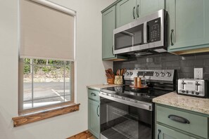 Eine Küche mit Mikrowelle, Toaster, Backofen und einem Fenster mit Blick auf einen Parkplatz.