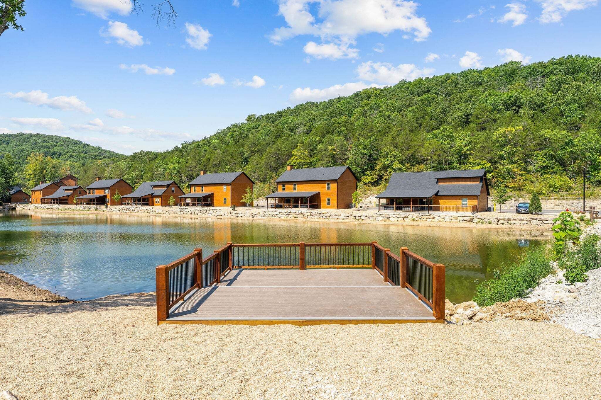 A lakeside resort with wooden cabins, a dock, and a forested backdrop.