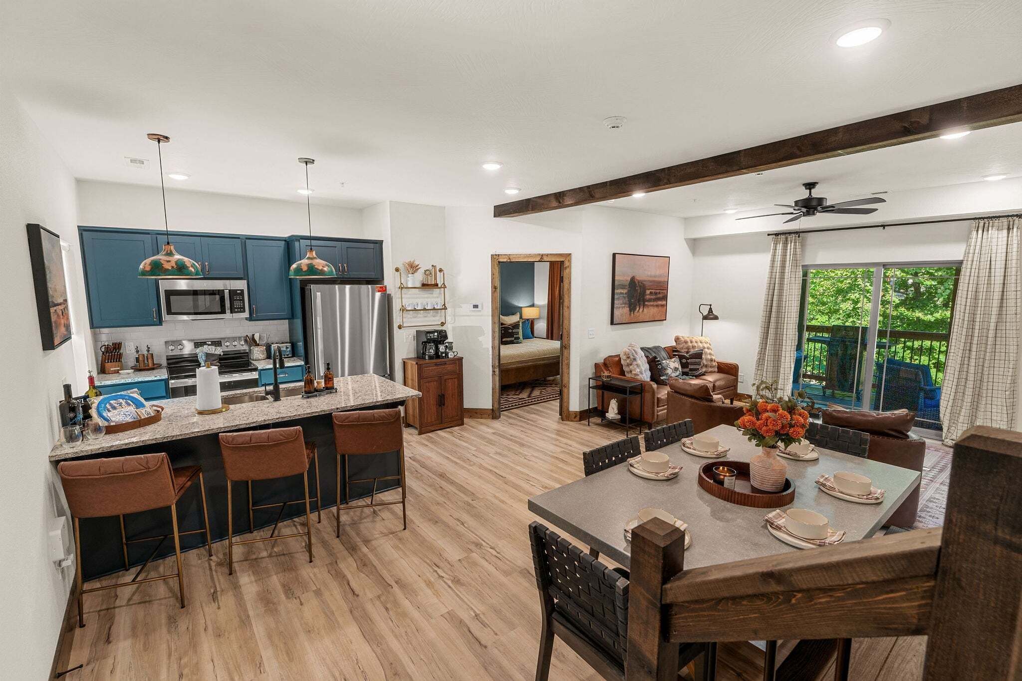 A modern kitchen with blue cabinets, a central island with bar stools, and a dining area with a wooden table set for four.