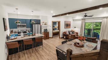 A modern kitchen with blue cabinets, a central island with bar stools, and a dining area with a wooden table set for four.