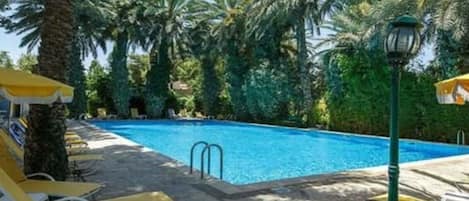 Una piscina con sillas de descanso y un farol.