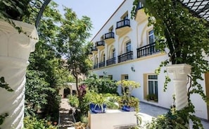 Un patio con un edificio que tiene balcones y un jardín con plantas en macetas.