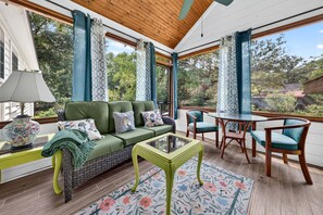 A cozy living area with a sofa, chairs, a table, and a view of the outdoors. - Sweetgrass Cottage, Pond Views, Pet Friendly, Boat Trailer Parking & Fireplace (Georgetown)