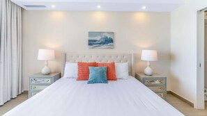 Une chambre à coucher avec un grand lit, deux tables de chevet avec des lampes, une tête de lit et un tableau au mur.