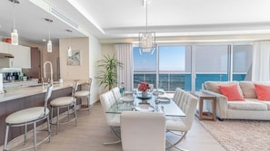 A modern living space with a dining area, kitchen, and a balcony with a view. - Verano 1601 – Spacious Corner Condo (Puerto Peñasco)