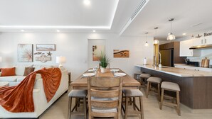 Uma sala de estar moderna com área de jantar, cozinha com balcão e uma janela grande.
